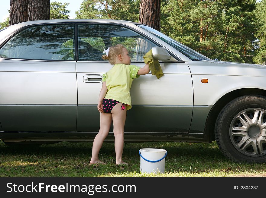 The little girl washes the car on the nature. The little girl washes the car on the nature.