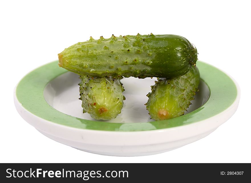 Three little green cucumbers one on one on plate