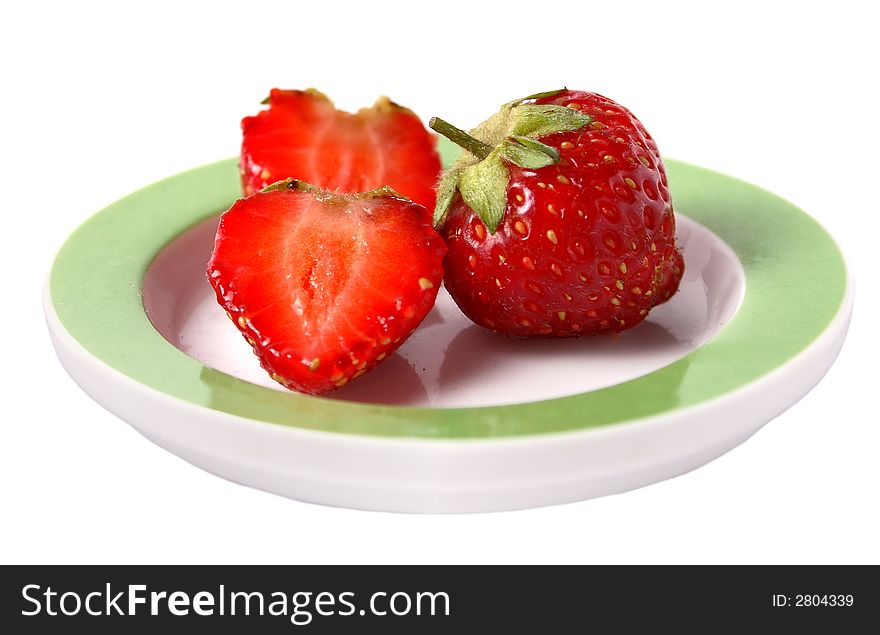 One whole and two halves of strawberry on a saucer. One whole and two halves of strawberry on a saucer