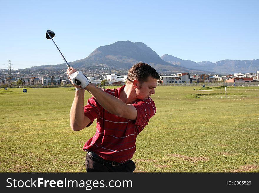 Young golfer on the driving range taking a back swing. Young golfer on the driving range taking a back swing