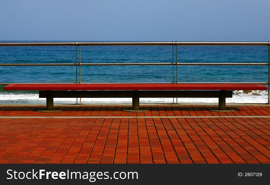 Wooden red bench on the beach with blue sky. Wooden red bench on the beach with blue sky