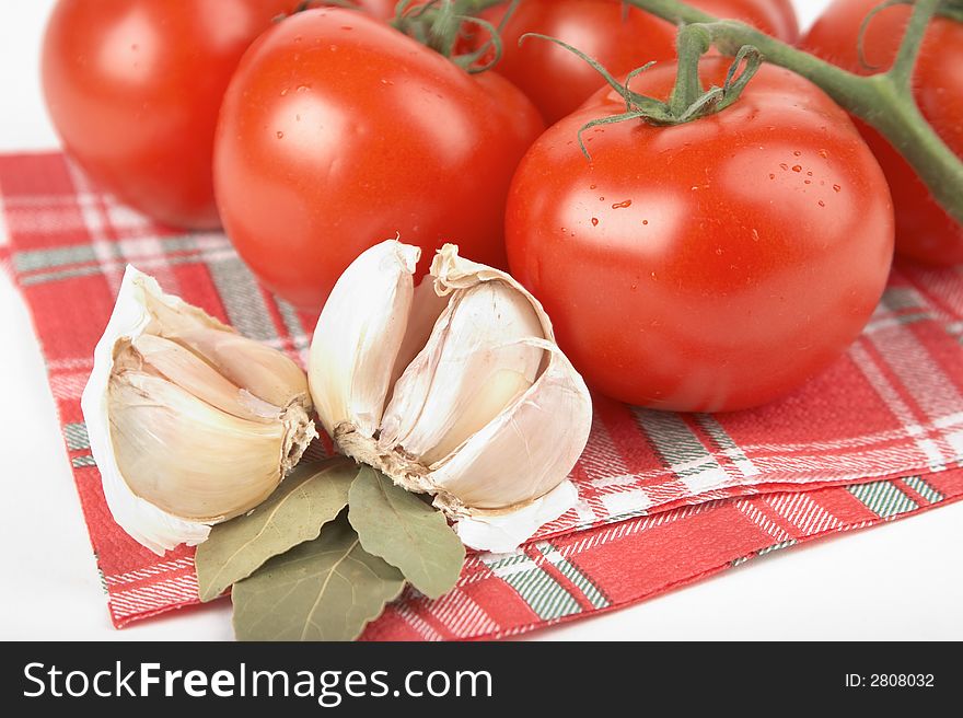 Tomatoes, garlic, bay leaf on white background;