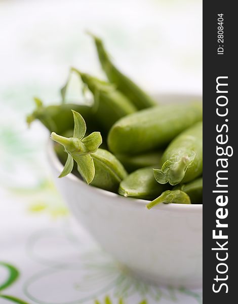 Fresh peas in white bowl, shallow focus