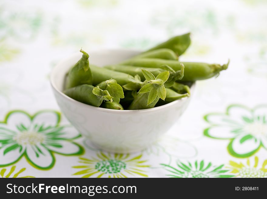 Fresh peas in white bowl, shallow focus