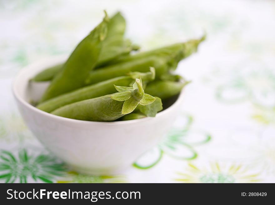 Fresh peas in white bowl, shallow focus