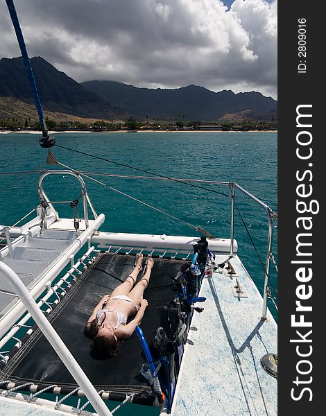 A young teenager sunbathing on the bow of a catamaran