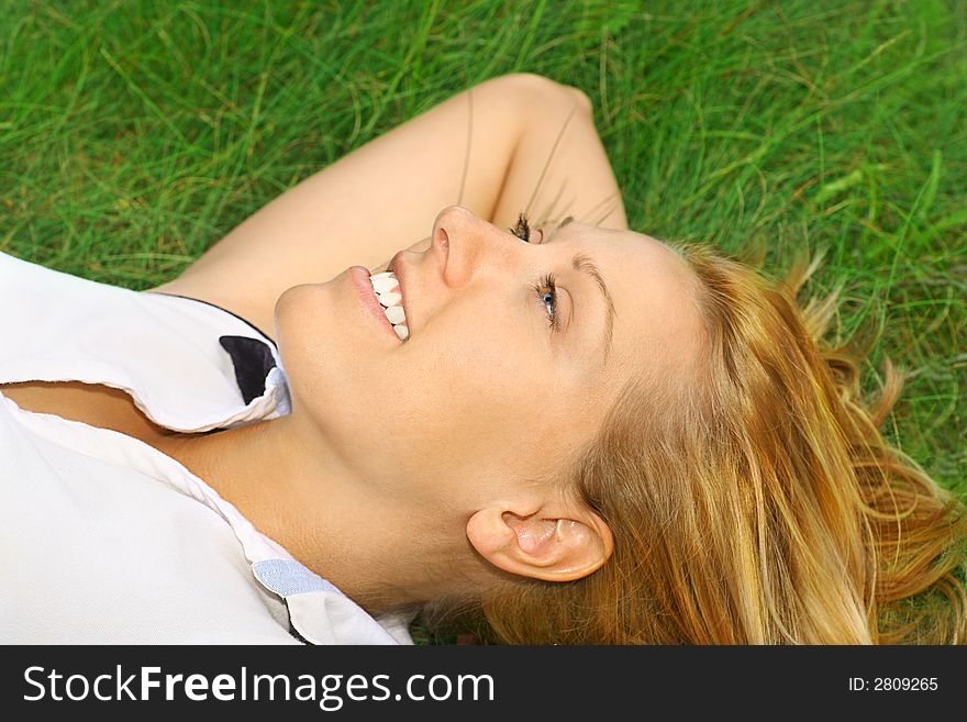 Attractive smiling woman lying on the green grass in the summer relaxing. Attractive smiling woman lying on the green grass in the summer relaxing