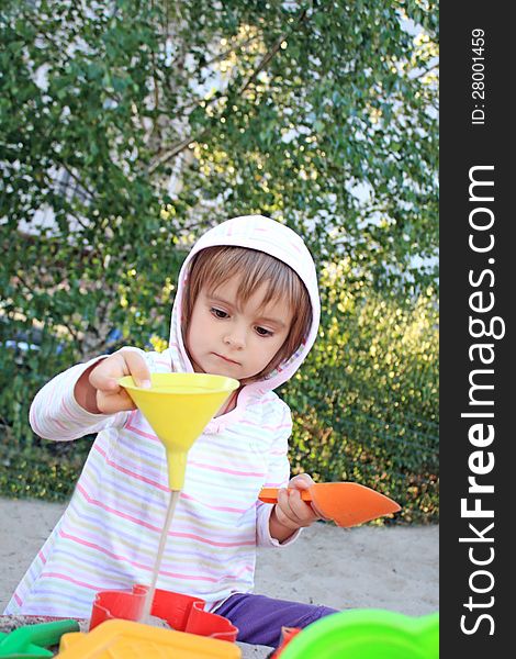 Little pretty girl while playing with funnel and sand, studying physics