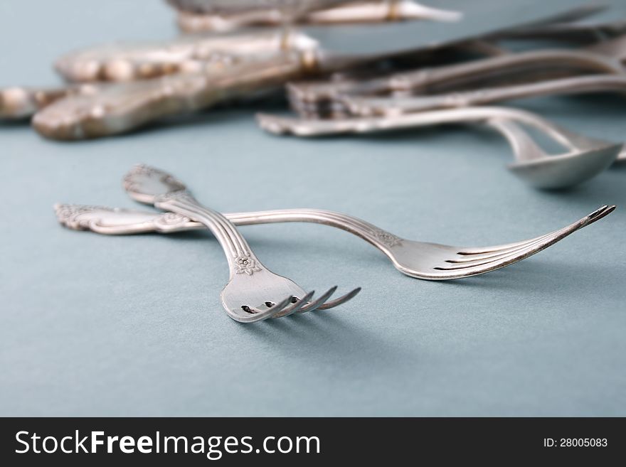 Retro style metallic forks and spoons on blue background. Retro style metallic forks and spoons on blue background.