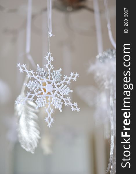 Hanging Christmas decoration snowflake on a background of white feathers. Hanging Christmas decoration snowflake on a background of white feathers