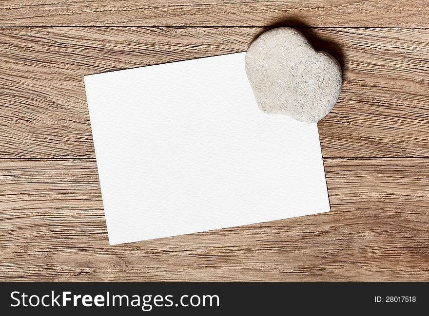 Stone in the shape of a heart and a piece for congratulations on a wooden background. Stone in the shape of a heart and a piece for congratulations on a wooden background