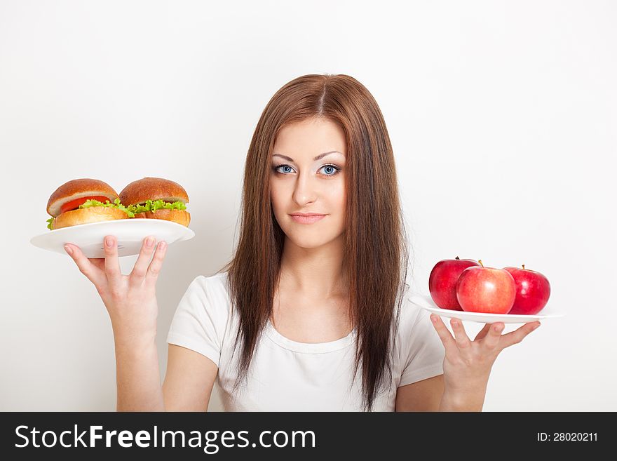 Woman holding two plates with junk food and apples. Woman holding two plates with junk food and apples