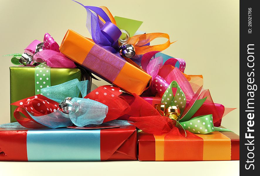 A stack of bright color presents in red, blue, orange, pink and green, with ties, tags and ribbons. A stack of bright color presents in red, blue, orange, pink and green, with ties, tags and ribbons.
