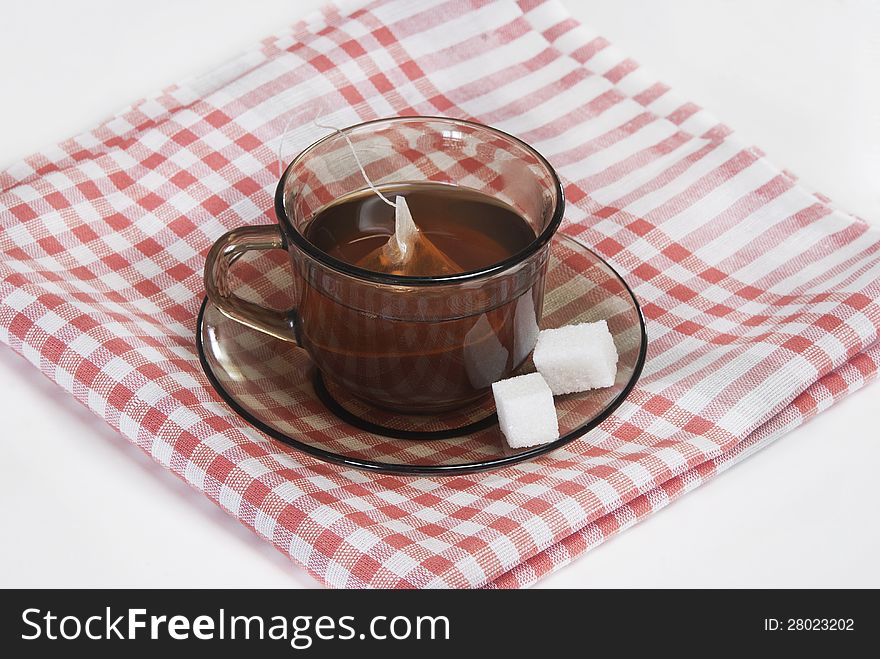 Cup of tea and two slices of sugar on a saucer on a white napkin. Cup of tea and two slices of sugar on a saucer on a white napkin