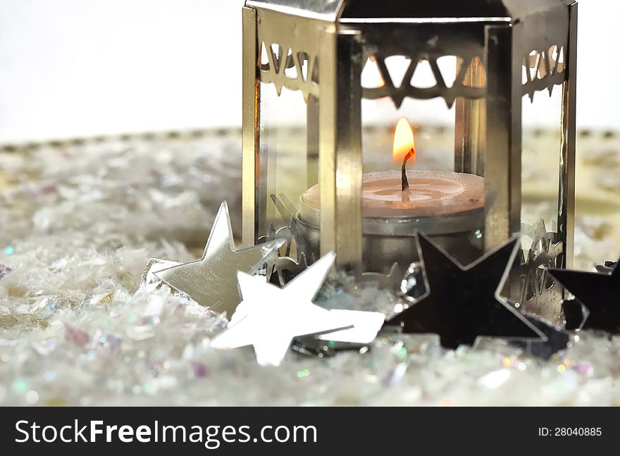 Silver stars against a lit candle holder in a tray. Silver stars against a lit candle holder in a tray
