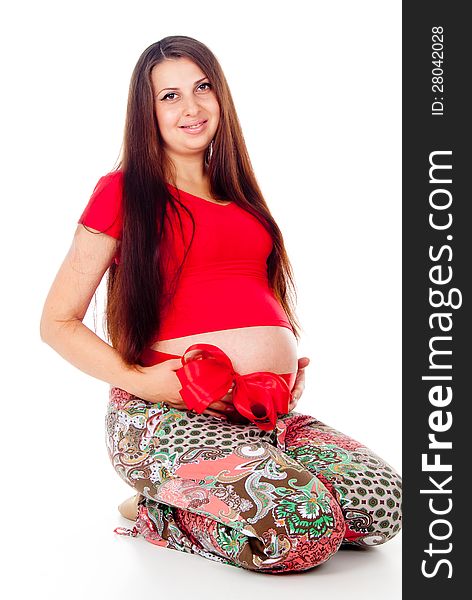 Pregnant girl with a red bow on her stomach on white background