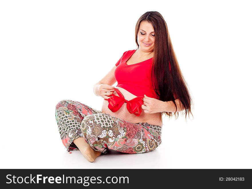 Pregnant girl corrects red bow on her stomach