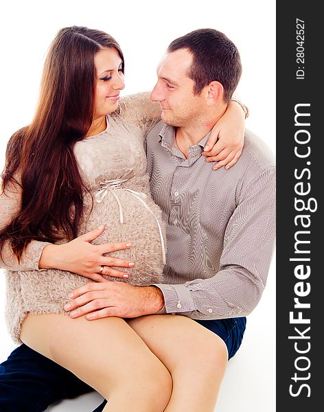 Dad keeps his pregnant wife on her knees on white background