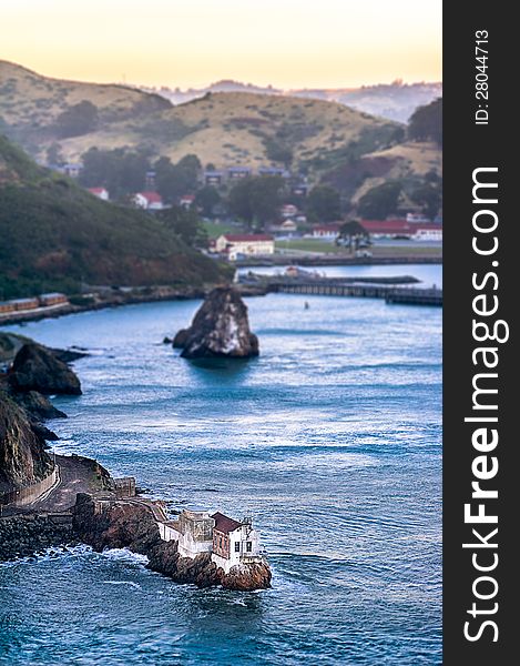 Small house on the rocks in the bay and distant hills