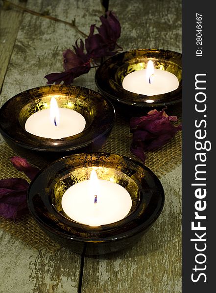 Three black and gold mottled tea-light holder on a rustic table. Three black and gold mottled tea-light holder on a rustic table