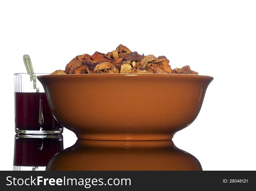 Brown ceramic bowl of homemade dried apples and a glass of transparent glass with a compote of the dried apples   on white background. Brown ceramic bowl of homemade dried apples and a glass of transparent glass with a compote of the dried apples   on white background.