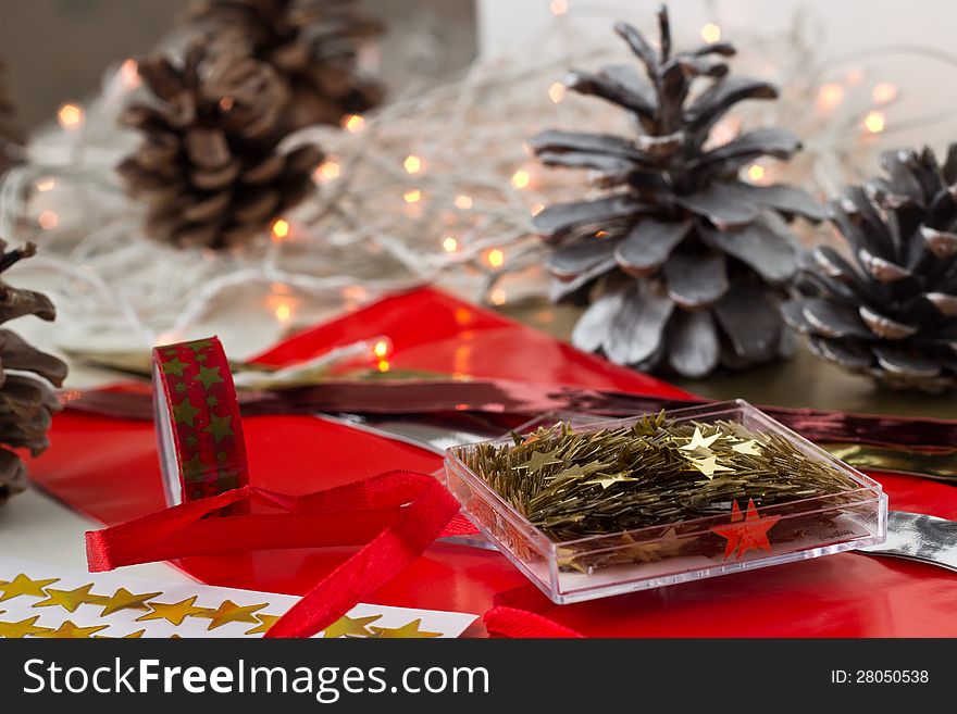 Christmas decoration stars, paper, masking tape prepared on the table. Christmas light and silver cones are on the background. Christmas decoration stars, paper, masking tape prepared on the table. Christmas light and silver cones are on the background.