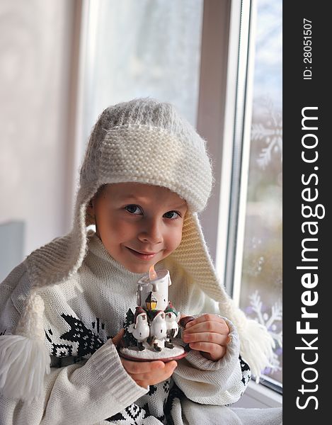 Winter boy sitting by the window in a white knitted cap. Winter boy sitting by the window in a white knitted cap
