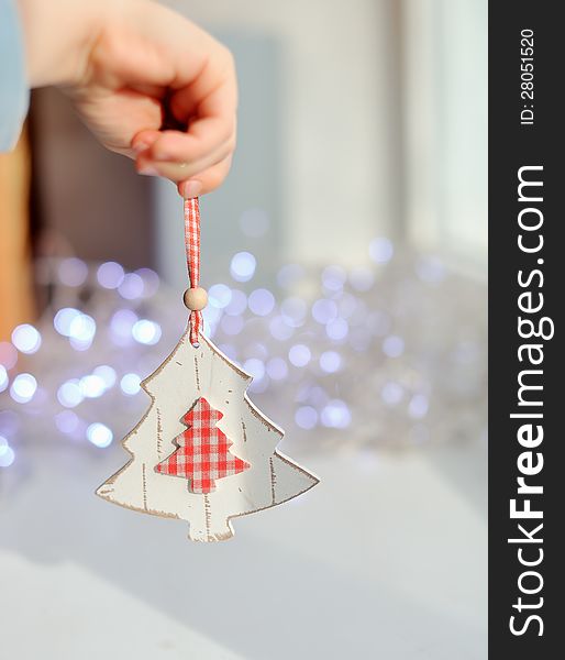 Against the background of lights garland baby hand holding a Christmas toy