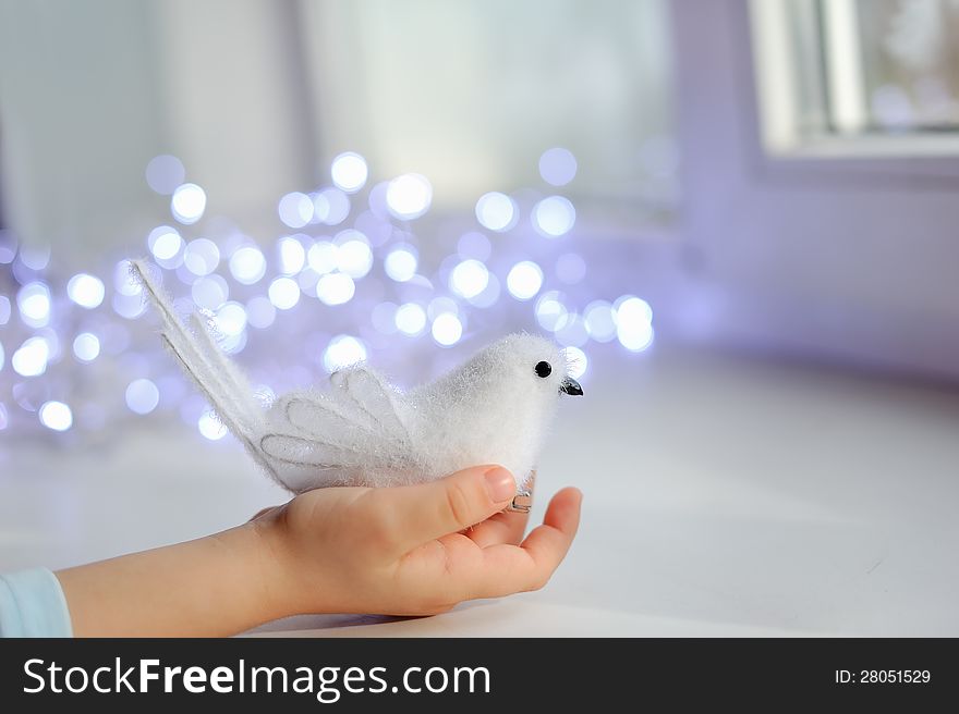 Against the child's hand lights garland with white bird. Against the child's hand lights garland with white bird
