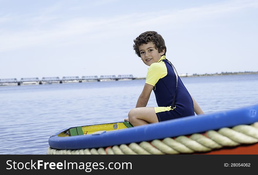 Boy sits in small boat looking this way. Boy sits in small boat looking this way.