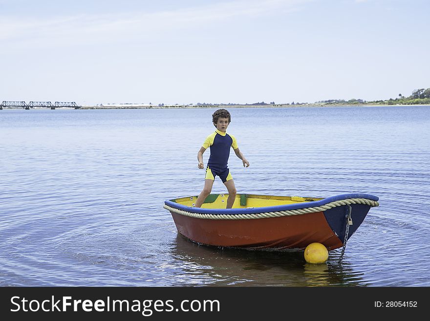 Boy standing in and rocking small boat. Boy standing in and rocking small boat.