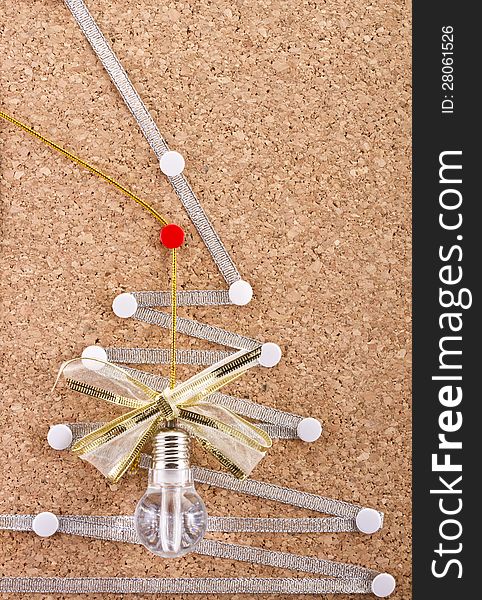 Part of a cork-board  with celebration idea lamp, festive bow and improvised silver Christmas tree on it. Part of a cork-board  with celebration idea lamp, festive bow and improvised silver Christmas tree on it.