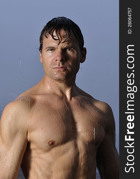 shirtless man standing in rain with stern look on face. shirtless man standing in rain with stern look on face