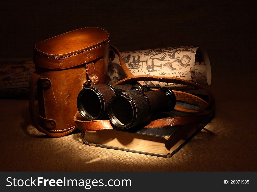 Still life with old binoculars on ancient book near leather case