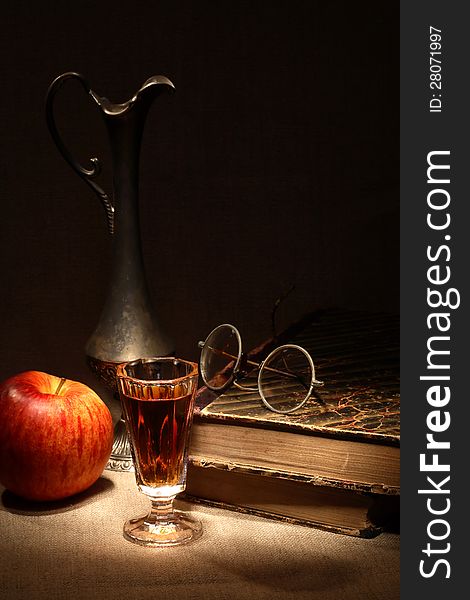 Vintage still life with apple and drink near old book on canvas surface