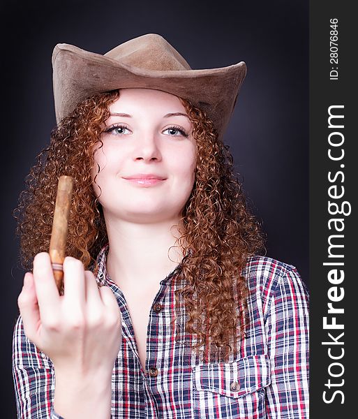 Portrait of a curly girl with a cigar on a dark background. Portrait of a curly girl with a cigar on a dark background