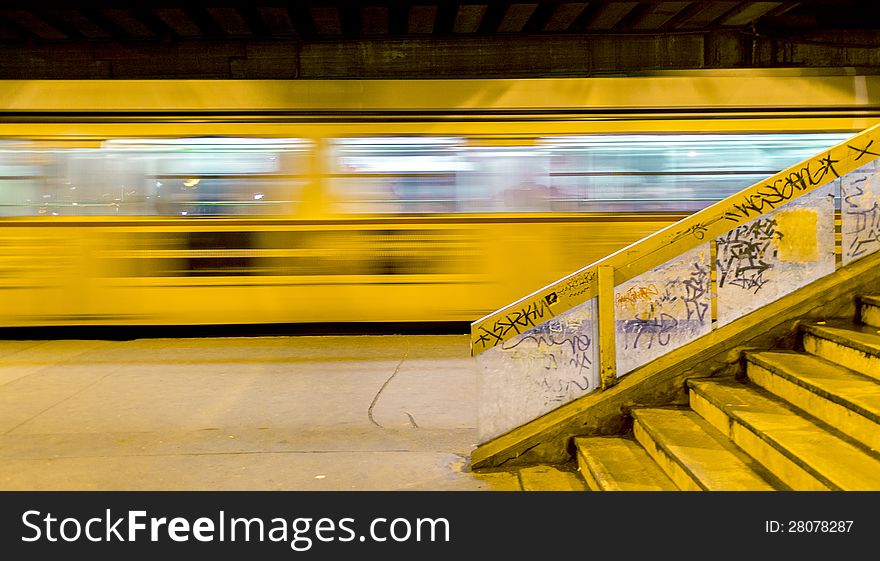 Tram number two runs out from the stop, under a bridge. On the right side there are the stairs to the bridge, decorated with graffties. Tram number two runs out from the stop, under a bridge. On the right side there are the stairs to the bridge, decorated with graffties