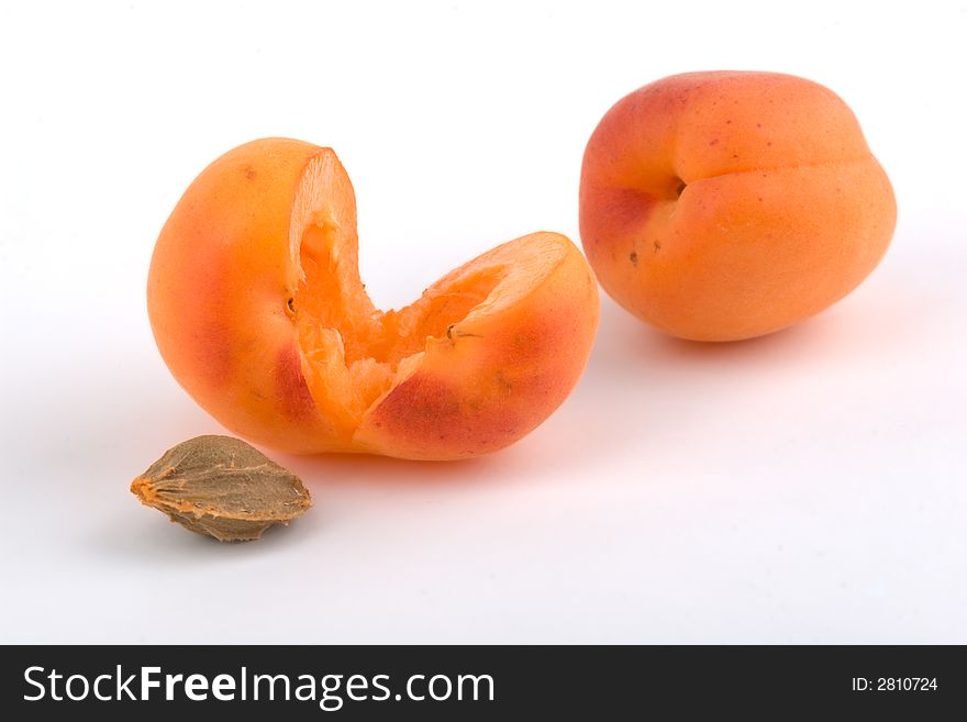 Two apricots and stone on white background