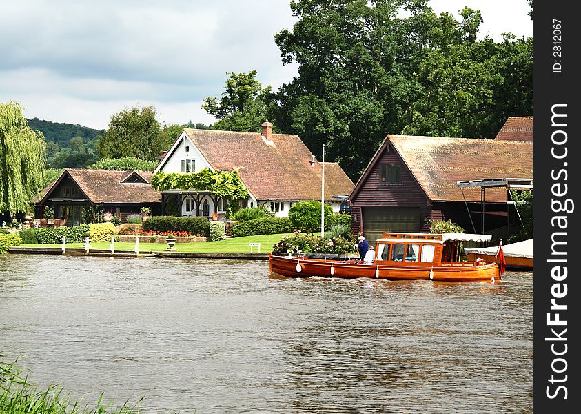 Pleasure Boat on the River Thames in England with Riverbank Houses in the background