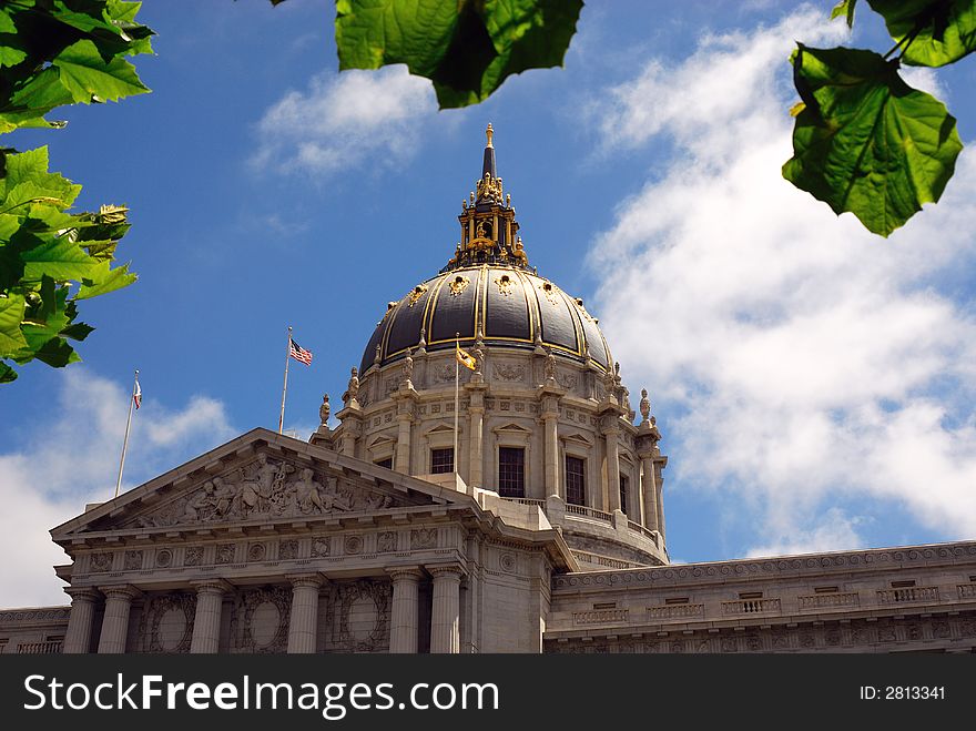 Partial view of beautiful San Francisco City Hall framed by bright green leaves