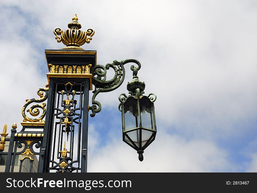 Beautiful lamp and wrought iron work with golden inlays against a dramatic sky. Beautiful lamp and wrought iron work with golden inlays against a dramatic sky