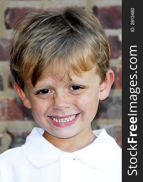 Portrait of a cute smiling boy with a brick wall as the background. Portrait of a cute smiling boy with a brick wall as the background.