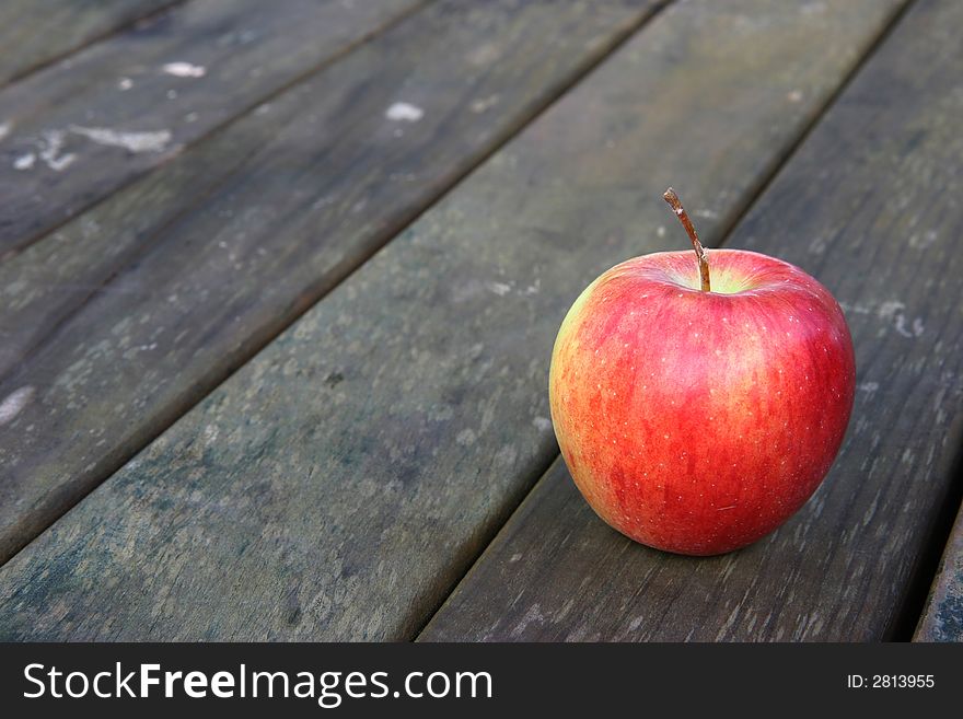 Red apple on a weathered wooden garden or park table