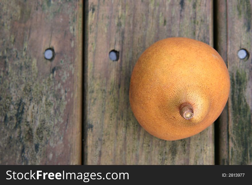 A yellow brown ripe pear on a weathered wooden park table