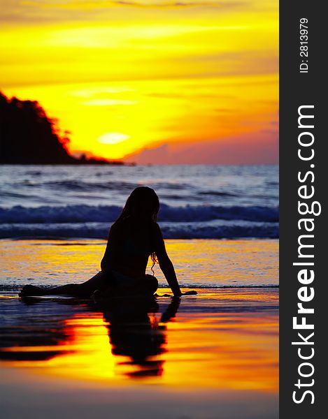 View of a girl lounging on tropical beach during sunset. View of a girl lounging on tropical beach during sunset