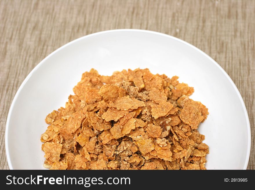 Simple bowl and cornflakes on a brownish beige mat. Simple bowl and cornflakes on a brownish beige mat