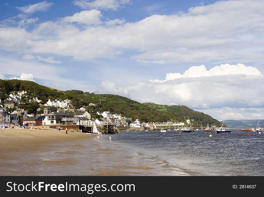 Landscape across beach and estuary towards mountains and clouds. Welsh seaside town with space for text.