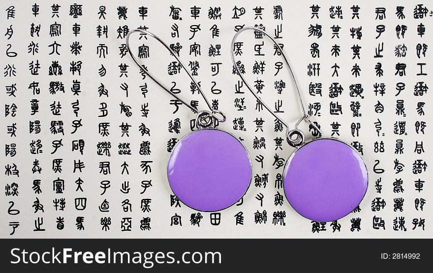 Purple fashion earrings on an Asian background. Purple fashion earrings on an Asian background