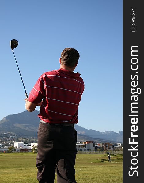 Young golfer following the ball against a blue sky. Young golfer following the ball against a blue sky