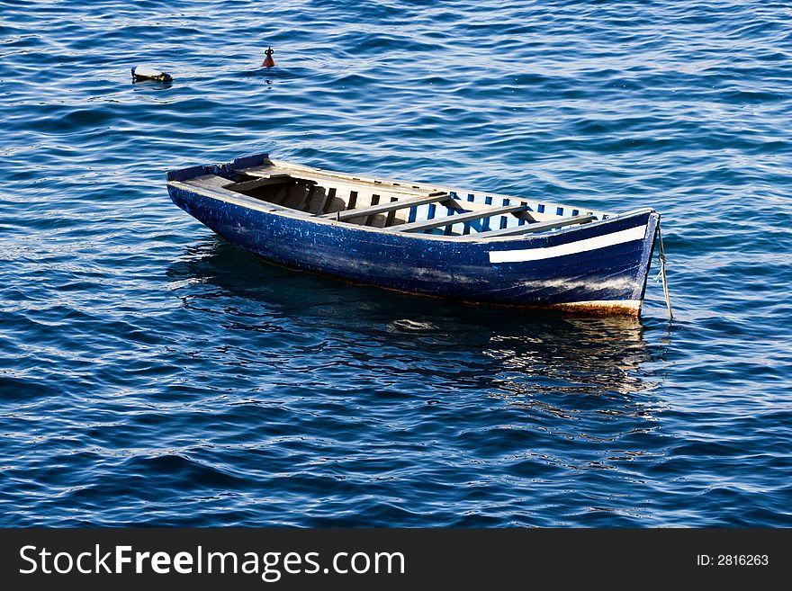 Small wooden fishing boat at anchor in the sun